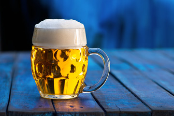 Glass of beer on the blue wooden background.