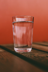 glass of water on wooden table with red background 