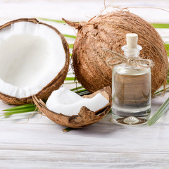 Coconut oil in glass jar and shell pieces on white wooden table