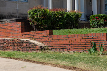 Old brick retaining wall in front of newer red brick retaining wall, horizontal aspect