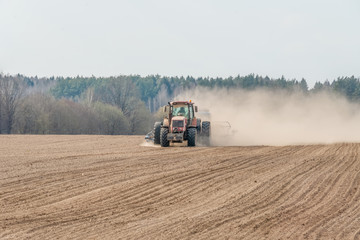 Obraz premium Farmer in tractor preparing land with seedbed cultivator as part of pre seeding activities in early spring season of agricultural works at farmlands.