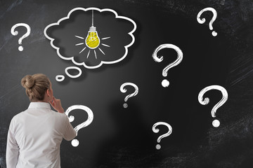 finding solution to problem or answer to question concept with woman looking at chalkboard with...