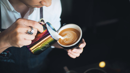 Fototapeta na wymiar Barista pouring milk to coffee espresso latte art in cafe