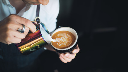Barista pouring milk to coffee espresso latte art in cafe