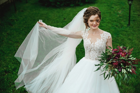 love of two people; the bride holds a beautiful bouquet; wedding photography bride with a bouquet on a red background; Wedding Dress