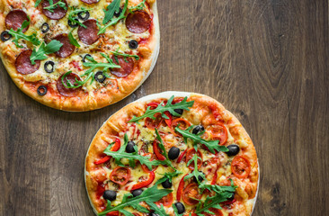 Pepperoni Pizza and Pizza with Mozzarella cheese, Tomatoes, pepper, olive, Spices and Fresh arugula. Pizza Margherita or Margarita on wooden table background