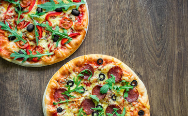 Pepperoni Pizza and Pizza with Mozzarella cheese, Tomatoes, pepper, olive, Spices and Fresh arugula. Pizza Margherita or Margarita on wooden table background