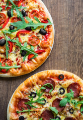 Pepperoni Pizza and Pizza with Mozzarella cheese, Tomatoes, pepper, olive, Spices and Fresh arugula. Pizza Margherita or Margarita on wooden table background