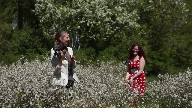 the photographer takes pictures of the model in a dress among the green forest