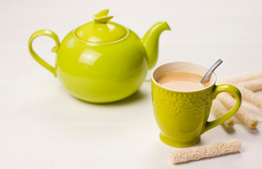  Green teapot and a cup of tea with milk. Green color. Breakfast with green dishes