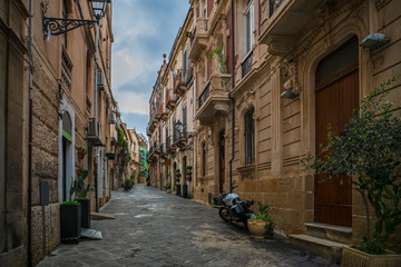Fototapeta na wymiar Narrow street in typical italian town on the island Ortigia in Syracuse in Sicily, south Italy