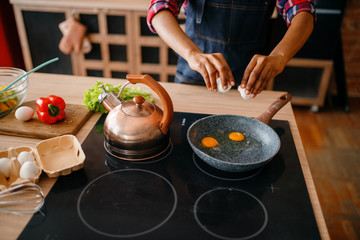 Black female person cooking fried eggs on kitchen