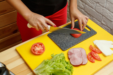 Woman slice tomato. Cooking from fresh vegetables