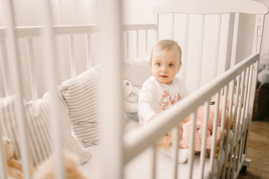 The Toddler Sits In A Crib And Plays.