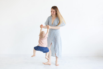 Happy mother and two-years-old baby boy playing at home in bedroom. Cozy family lifestyle in bright sunny white interior. Family Joyfully time together, joint pastime with the child, funny games