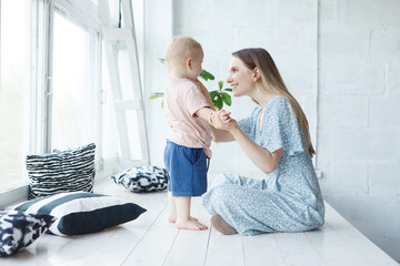 Young, caring mother looks at her baby with great love and warmth, and she is happy in motherhood....