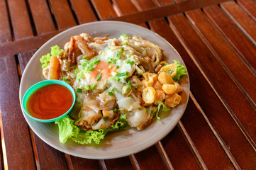 Stir-fried rice noodle with chicken, squid, fry egg and lettuce