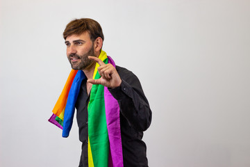 Portrait of handsome young man with gay pride movement LGBT Rainbow flag and brown hair holding up...