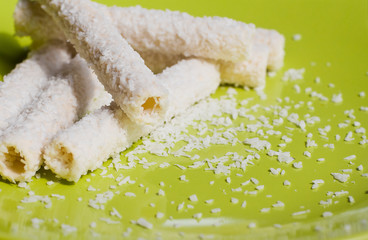 Coconut biscuits with vanilla cream. Cookies with coconut flakes. Coconut sweets on a green background