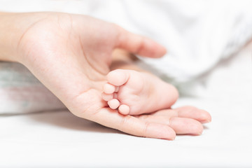 Foot of newborn is placed on the mother's hand.
