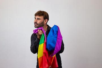 Portrait of handsome young man with gay pride movement LGBT Rainbow flag and brown hair in love,...