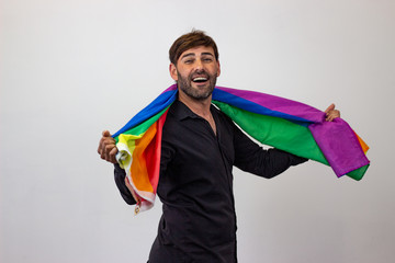 Portrait of handsome young man with gay pride movement LGBT Rainbow flag and brown hair and a funny...