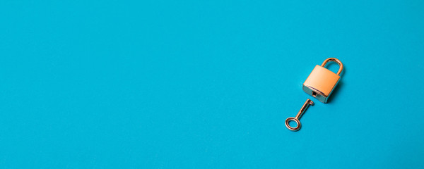 Flat lay protection concept. Locked padlock and key on the blue background.