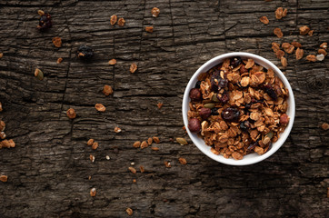Dry granola in a white bowl on a wooden background, top view, copy space.
