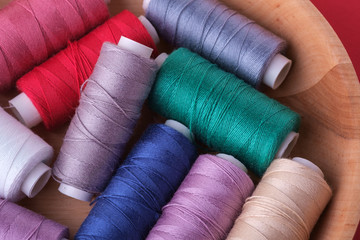 Top view close up of scattered colorful cotton thread coils in wooden plate