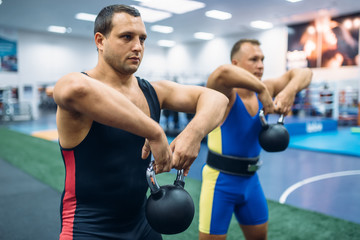 Fototapeta na wymiar Strong male lifters doing exercise with kettlebell