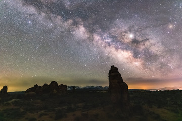 Starry night with the Milky Way stretching across the sky over rock formations in the wilderness....