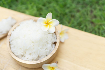 Fototapeta na wymiar Close up white rice in wooden bowl with green nature background, healthy food, selective focus
