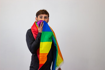 Portrait of handsome young man with gay pride movement LGBT Rainbow flag and brown hair speaking on the phone, their back facing the camera and looking at the camera. Isolated on white background.