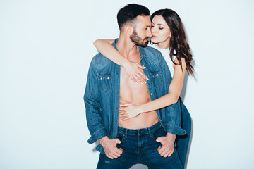 Naklejka premium pretty young woman embracing bearded boyfriend on grey