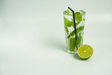 Glass of cold refreshing drink with ice,lime and mint on white background