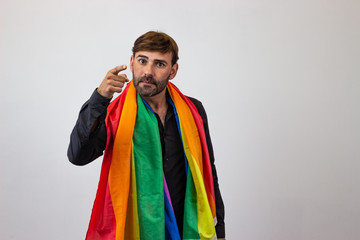 Portrait of handsome young man with gay pride movement LGBT Rainbow flag and brown hair giving a thumbs down, looking at the camera. Isolated on white background.