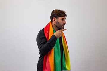 Portrait of handsome young man with gay pride movement LGBT Rainbow flag and brown hair giving a...