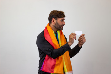 Portrait of handsome young man with gay pride movement LGBT Rainbow flag and brown hair giving a...