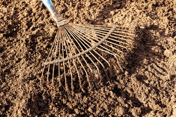 Metal rake on ground. Preparation soil for planting plants, gardening.