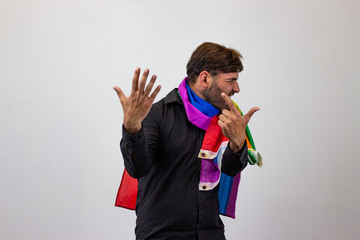 Portrait of handsome young man with gay pride movement LGBT Rainbow flag and brown hair screaming,...