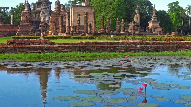 wide shot morning view of Sukhothai Historical Park at Mahathat temple reflecting in water, Thailand, Panning Left, Panning.