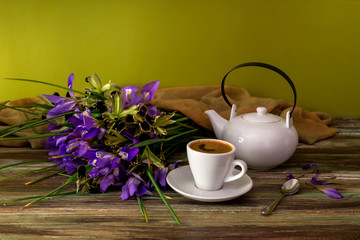 The bouquet of irises yellow and violet color close-up and cup of coffee