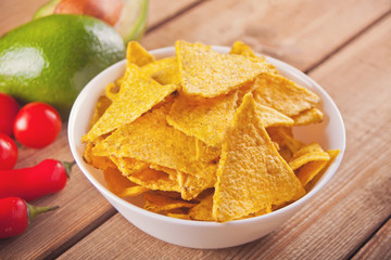 Mexican corn chips nachos with vegetables on the wooden table