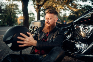Biker sitting on the ground against his chopper