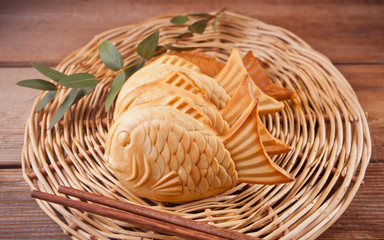 Obraz premium Taiyaki Japanese street food fish-shaped sweet filling waffle on wooden table.