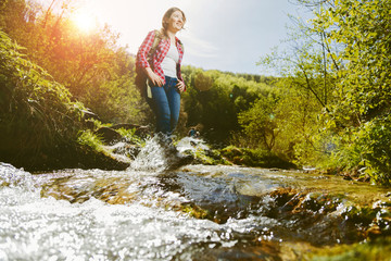 Woman crossing the river in the wild valley 