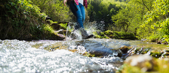 Woman crossing the river in the wild valley 