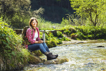 Wandernde Frau sitzend an einem Fluss.