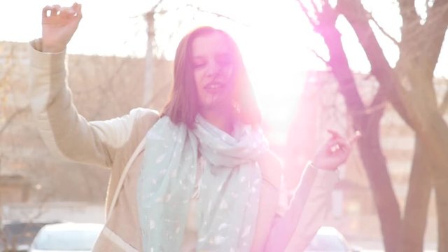 Young happy woman dancing in the rays of the spring sun. Slow motion