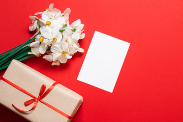 Kraft envelope with a blank sheet of paper and a red tulip on a red background, top view with space for text